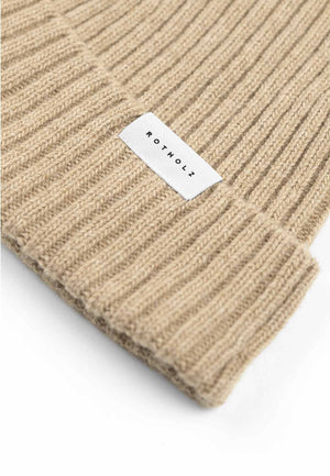 Close up of the brim of a ribbed beanie in beige.