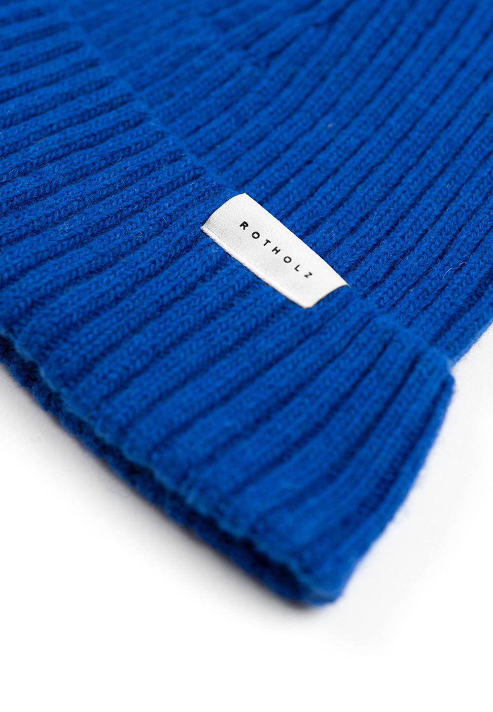 Close up of the brim of a ribbed beanie in cobalt blue.